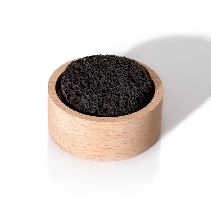 A round black Lava Rock Passive Diffuser by Plant Therapy rests inside a light wooden holder on a white background, casting a shadow to the right.