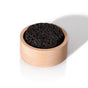 A round black Lava Rock Passive Diffuser by Plant Therapy rests inside a light wooden holder on a white background, casting a shadow to the right.