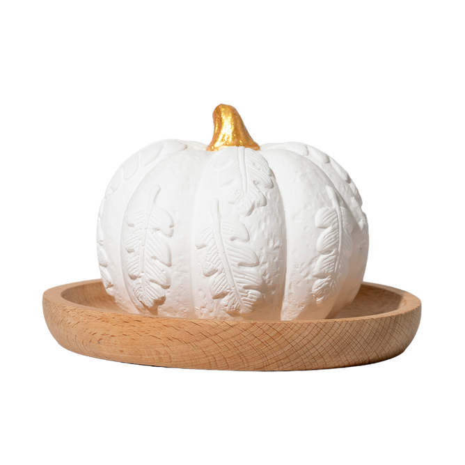 A white Pumpkin Passive Diffuser by Plant Therapy, featuring carved leaf patterns and a gold stem, rests on a round wooden tray against a plain white background—making it the perfect elegant addition to your fall décor or for gently diffusing your favorite essential oils.