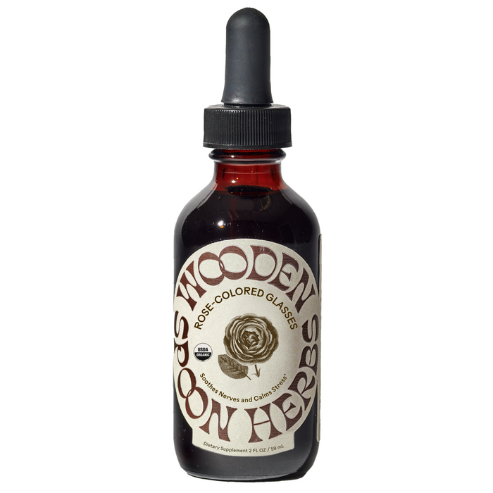 A brown glass dropper bottle labeled Wooden Spoon Herbs Rose-Colored Glasses Tincture, with a rose illustration, contains a mood-boosting dietary supplement for stress support.
