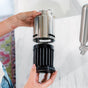 A person’s hands are opening a stainless steel Rorra Countertop Filter by Rorra to reveal the black Enfinity replacement filter cartridge inside, with a white countertop and part of a faucet visible in the background.
