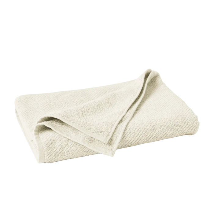 The Coyuchi Organic Bath Towel from the Air Weight Collection is neatly folded on a white background, showcasing its light beige color and soft textured absorbency with one corner draped over the rest.