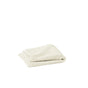 A neatly folded, light beige Organic Wash Cloth from Coyuchi's Air Weight Collection is placed on a white background.