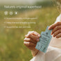 Someone holds Cymbiotika Liquid Colostrum Packets - Immunity + Digestive Support outdoors, with text highlighting benefits for immunity, gut and digestive health, plus hair, skin, and nails against a backdrop of blurred greenery.