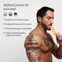 A tattooed, shirtless man eats from an orange packet. Text beside him highlights benefits: muscle recovery, better fitness performance, energy metabolism, and cognitive function—powered by advanced support from Cymbiotika Liposomal Advanced Creatine Packets - Muscle Tone + Recovery Support. Title reads: Refined power for your year.