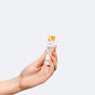 A hand holds a small tube labeled Thorne Complete Biotic Powder Packets, 3-in-1 Formula, with a white and yellow design, showcasing this prebiotic and probiotic supplement against a plain light gray background.