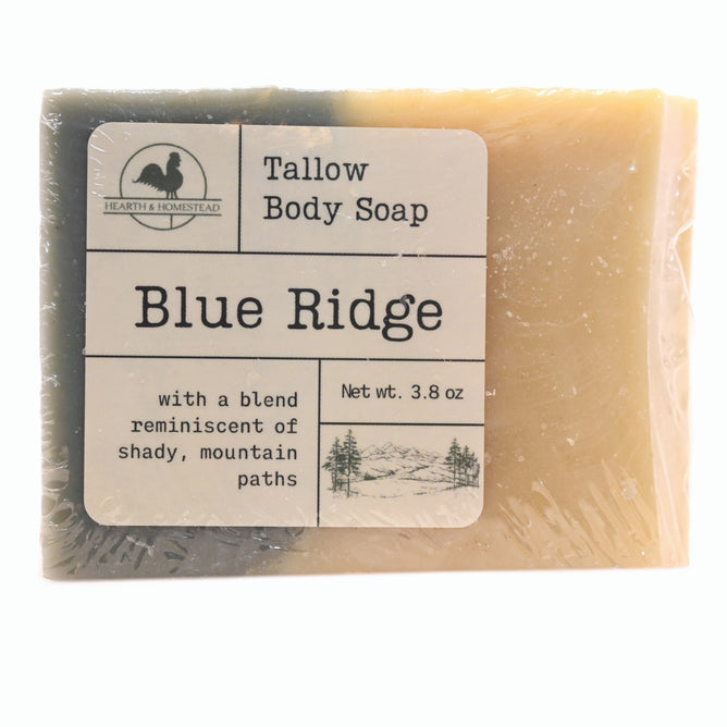 Blue Ridge Tallow Body Soap by Hearth and Homestead features a hand-drawn mountain label and text describing a scent reminiscent of shady, mountain paths. This natural handmade soap is tan with a dark corner.