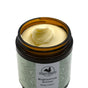 An open jar of Hearth and Homestead Magnesium Body Butter, featuring a creamy yellowish texture and decorative label in a brown glass container, is made with natural ingredients for muscle relaxation.