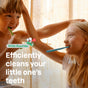 A smiling boy and girl brush their teeth together in the sunlight. Text on image: Efficiently cleans your kids teeth. With ATTITUDE little leaves Toothpaste with Fluoride, a vegan formula.