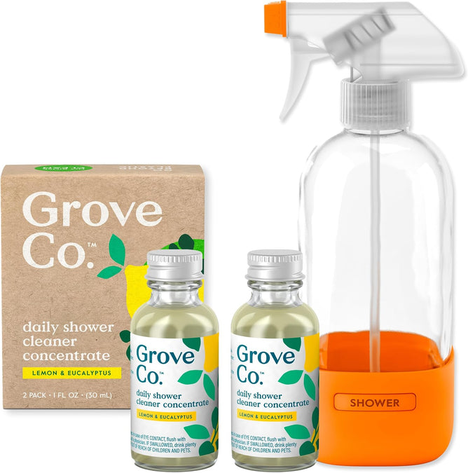 A cardboard box contains two Grove Co. Daily Shower Refill - Lemon bottles and a clear spray bottle with an orange base labeled SHOWER. This plant-based cleaner offers a lemon scent in a refillable, eco-friendly system.