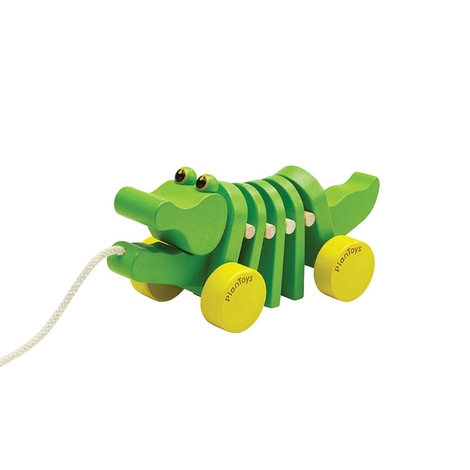 The Dancing Alligator Pull Toy for Toddlers by PlanToys is a green wooden pull-along toy with yellow wheels, moving segments, and cartoon eyes—a sustainable, eco-friendly choice for endless toddler fun.