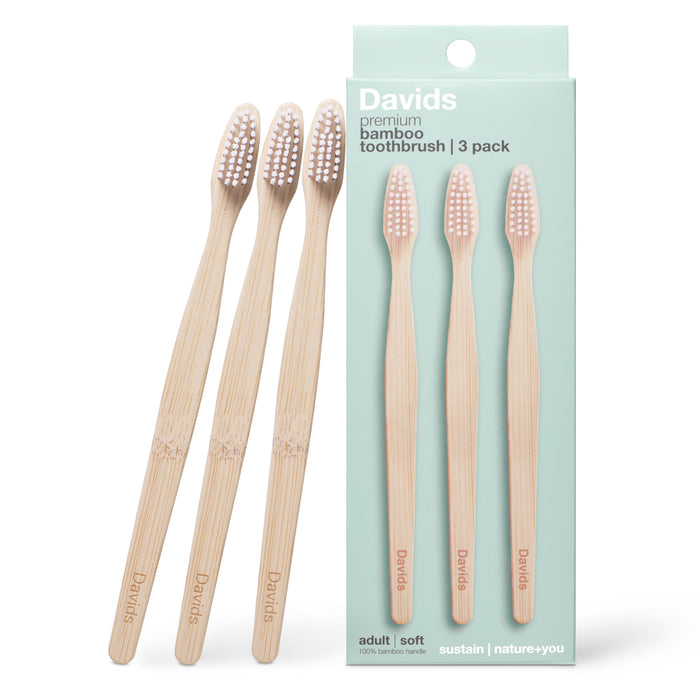Three bamboo toothbrushes are displayed next to a light green box labeled “Davids Premium Bamboo Toothbrush - Adult Soft,” featuring images of three eco-friendly toothbrushes on the packaging.