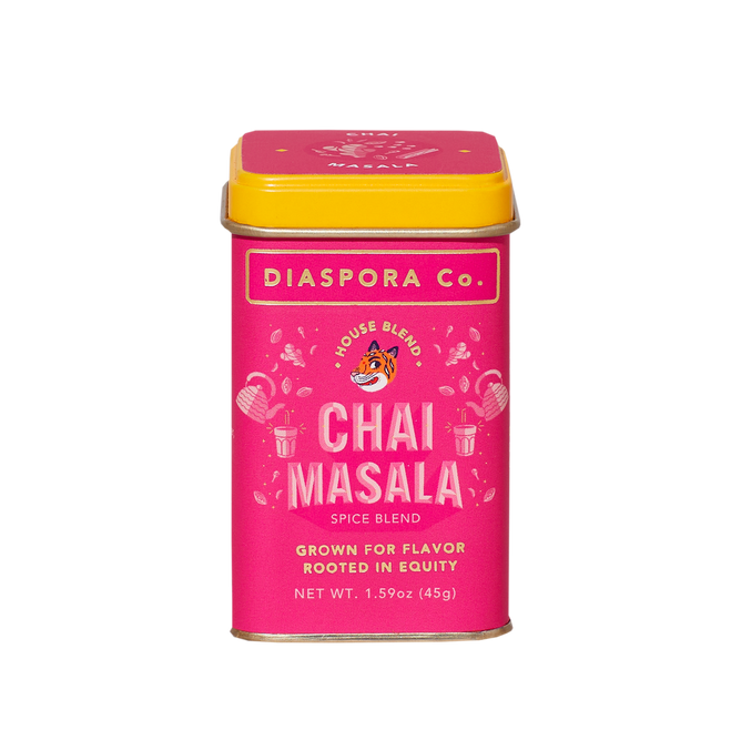 A rectangular tin of Diaspora Spice Co. Chai Masala features a bright pink label and yellow lid, showcasing “House Blend Chai Masala” made from single-origin spices grown for flavor and equity.