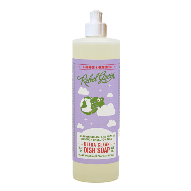 A bottle of Rebel Green Ultra Clean Dish Soap features a lavender and grapefruit scent from essential oils, with a purple label showing white clouds, a green earth graphic, and product details in green and orange text.