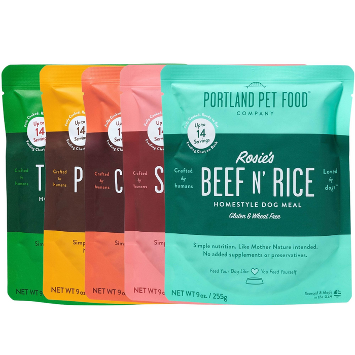 A variety pack from Portland Pet Food Company offers five colorful 9 oz pouches of human-grade dog meals, each with different flavors like Rosies Beef N Rice, prominently gluten and wheat-free in BPA-free packaging. Each pouch provides up to 14 servings and can be used as a meal or topper.