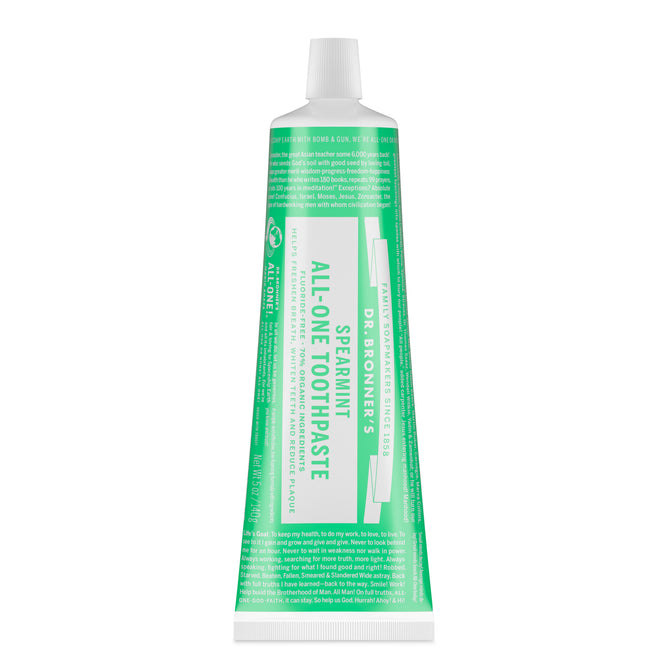 A tube of Dr. Bronner’s All-One Toothpaste stands upright with a white cap and green-and-white label, featuring its fluoride-free, organic formula and eco-friendly branding.