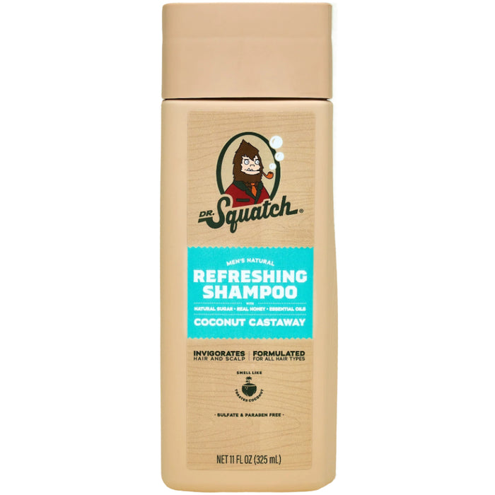 A beige 11 fl oz (325 mL) bottle of Dr. Squatch Refreshing Shampoo in Coconut Castaway scent, featuring a bearded cartoon figure on the label. It highlights soothing jojoba oil, invigorating benefits, and a sulfate-free formula.