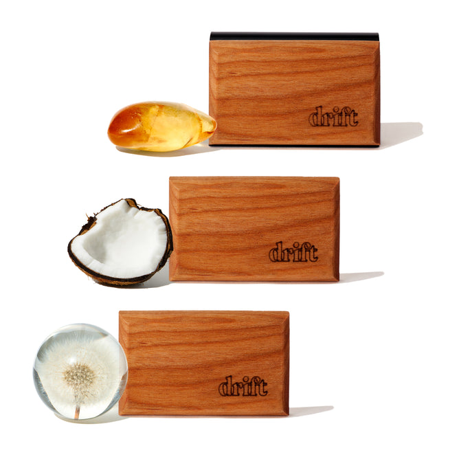 The Drift 3-Pack Wood Car Air Freshener Starter Kit includes three sustainably sourced wood blocks—each paired with amber resin, halved coconut, or a clear orb with dandelion seed—evoking essential fragrance oil blends.