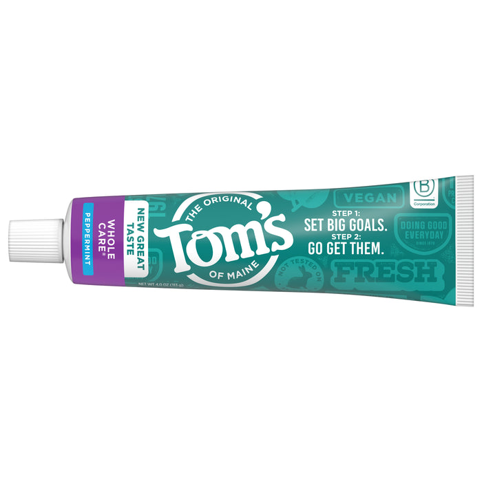 A tube of Tom’s of Maine Whole Care Fluoride Toothpaste in wild mint flavor, with “Set big goals. Go get them.” on teal and purple packaging, lies unopened and horizontally.
