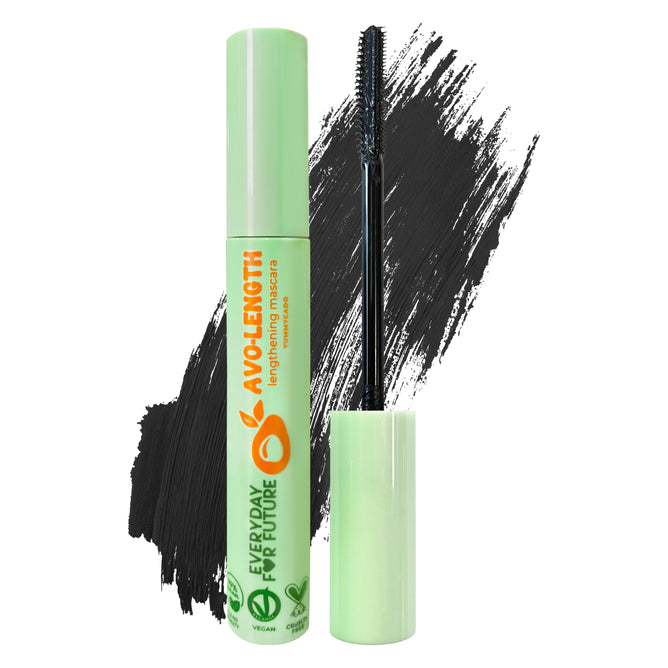 A tube of Lengthening Avocado Mascara, with an open applicator brush stands upright, showcasing green branding and Everyday For Future. Behind it, mascara strokes and half an avocado emphasize its natural theme, infused with Organic Avocado Oil to support lash growth.