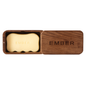 The Body Sculpting Set by Ember Wellness features a rectangular wooden box with a matching EMBER-engraved lid, containing a light yellow, curved Body Serum Bar also marked EMBER.