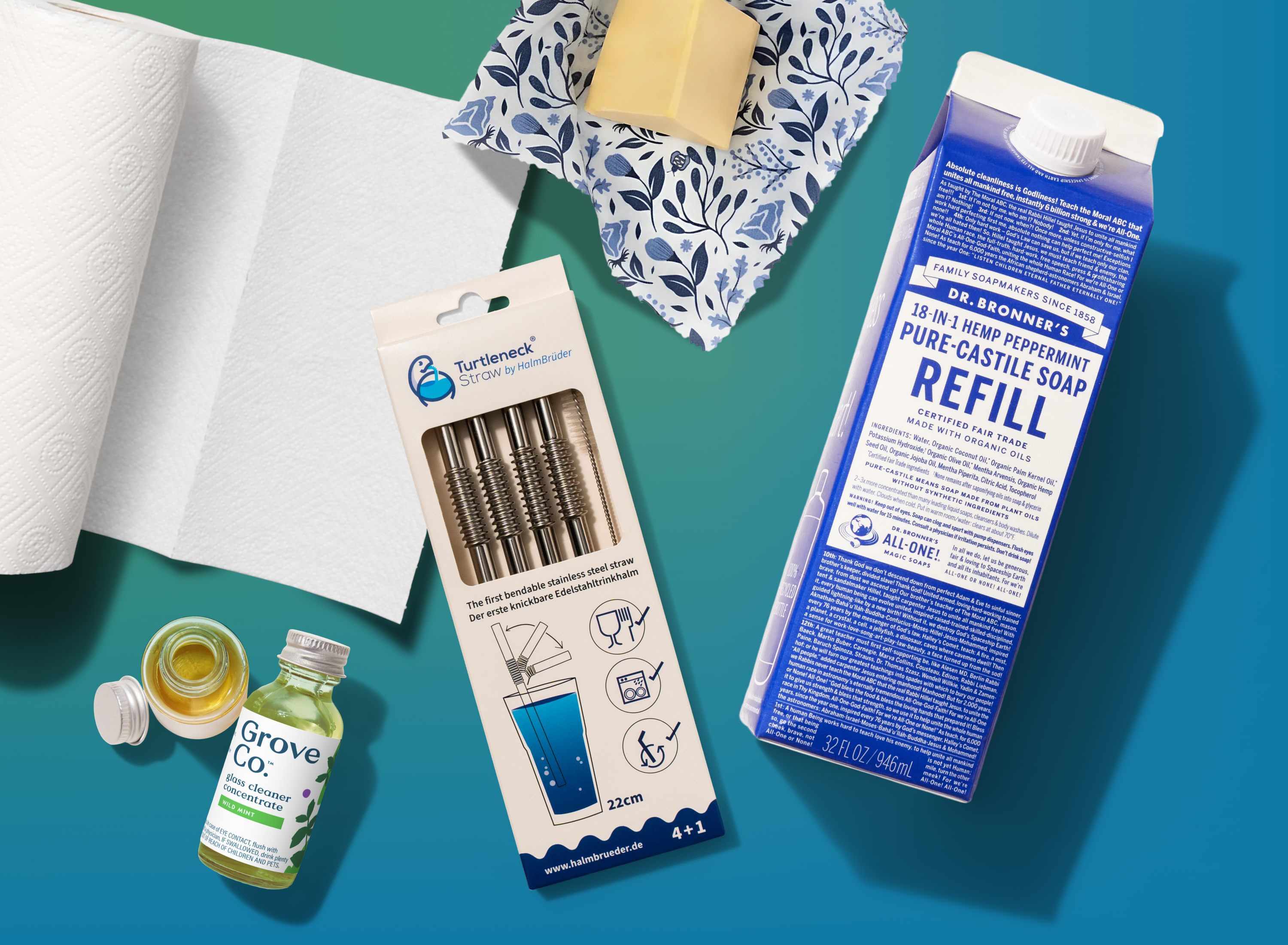 A flat lay of eco-friendly products, including a carton of Dr. Bronner’s soap refill, a box of reusable straws, a Grove Co. cleaning concentrate, a roll of paper towels, and a reusable cloth with a bar of soap.