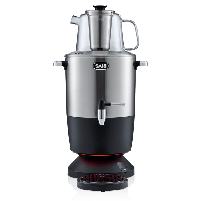 The SAKI Electric Samovar, featuring a sleek stainless steel design with a glass teapot on top, front spout, and a black base with a red-lit drip tray, offers an efficient keep warm function to maintain your tea at the perfect temperature. Shown on a white background.