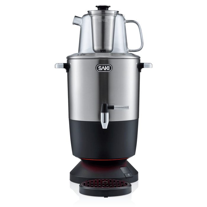 The SAKI Electric Samovar, featuring a sleek stainless steel design with a glass teapot on top, front spout, and a black base with a red-lit drip tray, offers an efficient keep warm function to maintain your tea at the perfect temperature. Shown on a white background.