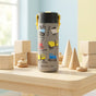 The Elemental Stainless Steel Kids Water Bottle, 18oz, in gray with construction vehicle designs and a pop fidget handle, sits on a wooden table among blocks and toys in a bright, sunlit room.