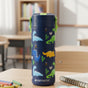 An Elemental Stainless Steel Kids Water Bottle, 18oz, with colorful dinosaur designs and a pop fidget handle sits on a classroom desk. The blue, leakproof bottle features the brand name printed at the bottom.