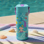 An Elemental Stainless Steel Kids Water Bottle, 18oz, with mermaid and sea-themed designs sits on a pastel-striped towel by the pool, surrounded by seashells.