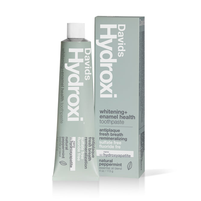 A tube and box of Davids Enamel Health + Whitening w/nano-hydroxyapatite Toothpaste, with a mint green design and white text, promotes fresh breath, fluoride-free formula, and natural peppermint flavor on the packaging.