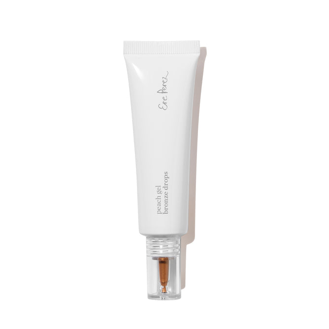 A white tube with a clear cap containing Ere Perez Peach Gel Bronze Drops liquid bronzer, ideal for sensitive skin, on a plain white background.