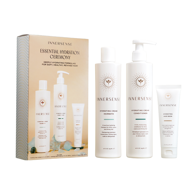 The Innersense Organic Beauty Essential Hydration Ceremony boxed set features a moisturizing shampoo, hydrating cream conditioner, and nourishing hair mask in sleek white bottles for beautifully hydrated hair.