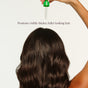 A person with long, wavy brown hair applies Everist’s EverBoost Multi-Peptide Scalp Serum with a dropper. Text reads: Promotes visibly thicker, fuller-looking hair. The image features a clean, white background.