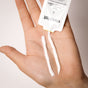 A hand displays two lines of waterless shampoo from a tube labeled Everist The Shampoo Concentrate Sample, showcasing sustainable haircare.