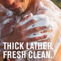 A man washes his shoulder with a thick, white lather of Every Man Jack Hydrating Body Wash for Men, made from naturally-derived ingredients. White text at the bottom reads, “THICK LATHER. FRESH CLEAN.”.