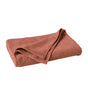 A rust-colored, textured Coyuchi Air Weight® Organic Towel is neatly folded and placed on a plain white surface, with one corner slightly turned over.