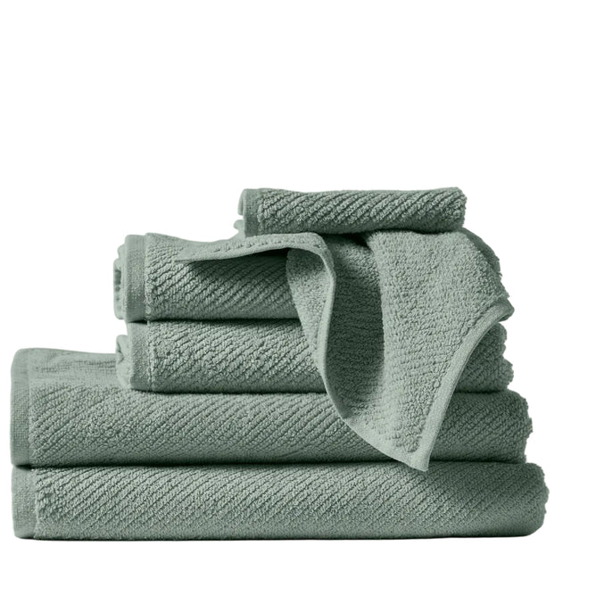 A neatly stacked set of four Coyuchi Air Weight® Organic Towels in sage green, crafted from absorbent organic cotton in assorted sizes, rests on a white background, with one towel casually draped over the others.