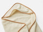 The Coyuchi Cloud Loom™ Organic Baby Hooded Towel and Bath Mitt Set, shown in beige with light brown trim, is laid flat on a white surface with one corner folded over.