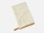 A cream-colored rectangular baby bath mitt with tan fabric trim and a small loop, shown lying flat on a white background—designed to perfectly complement the Coyuchi Cloud Loom™ Organic Baby Hooded Towel for a cozy and gentle bath time.