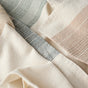 A close-up of cream-colored woven fabric with thin, textured stripes in muted pastel colors—light blue, peach, and beige—showcases the soft drape and expert craftsmanship of the Miraloma Organic Kitchen Towel set by Coyuchi. Thoughtfully yarn dyed for lasting color and durability, these towels combine style and quality in every fold.