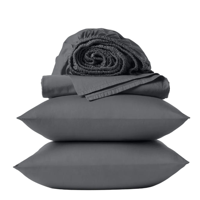 A set of dark gray bedding from Coyuchi’s Classic Organic Sateen Sheet Set, featuring two stacked pillows, a folded flat sheet, and a rolled fitted sheet, all neatly presented against a plain light background. Made from GOTS certified organic cotton, this collection delivers breathable comfort with superior eco-friendly quality.