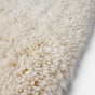 Close-up of the Coyuchi Shag Organic Bath Rug, featuring thick, soft off-white fibers in a plush shag texture—shown angled on a white background, this rug is perfect for bringing cozy comfort to your bathroom floor.