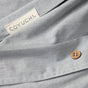 Close-up of the light gray Organic Crinkled Percale™ Duvet Cover by Coyuchi, featuring a sewn-in Coyuchi label and a small brown wooden button on the breathable organic cotton bedding.