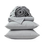 A neatly stacked set of Coyuchi’s Organic Crinkled Percale™ Sheet Set in light gray—including two pillows, a folded sheet, and a rolled fitted sheet—offers a breathable bedding experience and is displayed against a plain white background.