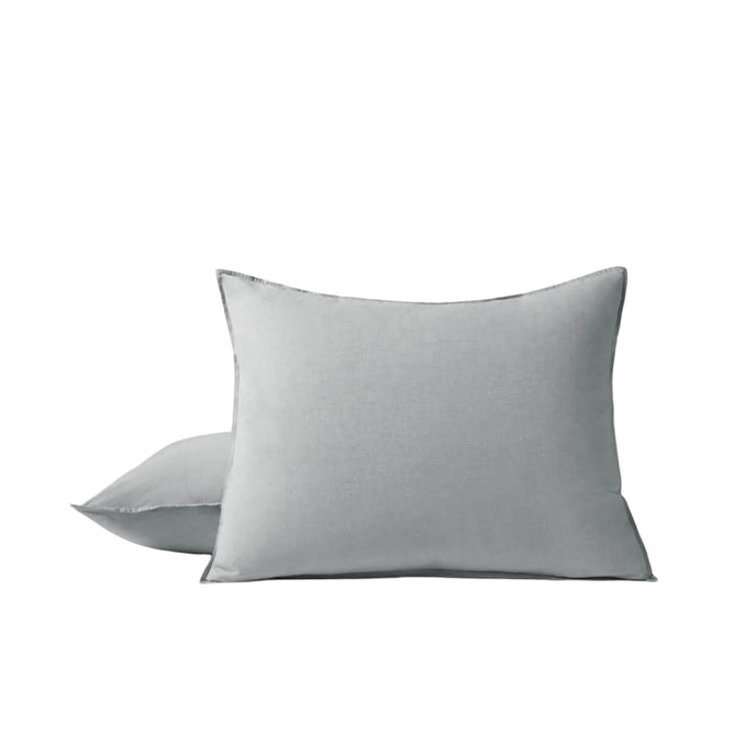 Two light gray Orgainc Crinkled Percale™ Shams by Coyuchi, one standing upright in front and the other lying flat behind it, are set against a plain white background. Made from crinkled percale for enhanced texture, these shams offer a relaxed look and pair perfectly with Coyuchi’s organic cotton sheet sham for breathable, comfortable bedding.