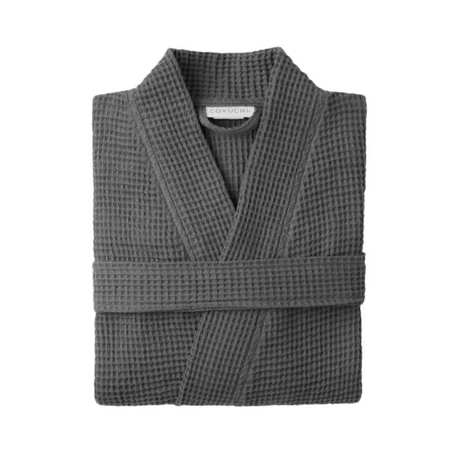 A folded Coyuchi Unisex Organic Waffle Robe in charcoal grey, crafted from organic cotton with a waffle weave, is displayed on a plain light grey background.
