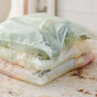 Three Compostable Zipper Gallon Bags by Full Circle, each filled with different items, are stacked on a speckled kitchen countertop. The visible branding highlights their use as sustainable food storage solutions.
