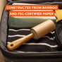 The Full Circle Lint Lifter Roller Wand, crafted from bamboo and FSC-certified paper, rests atop folded clothes in an open suitcase. Text reads: MADE FROM BAMBOO AND FSC-CERTIFIED PAPER, this eco-friendly lint remover is perfect for travel and daily use.